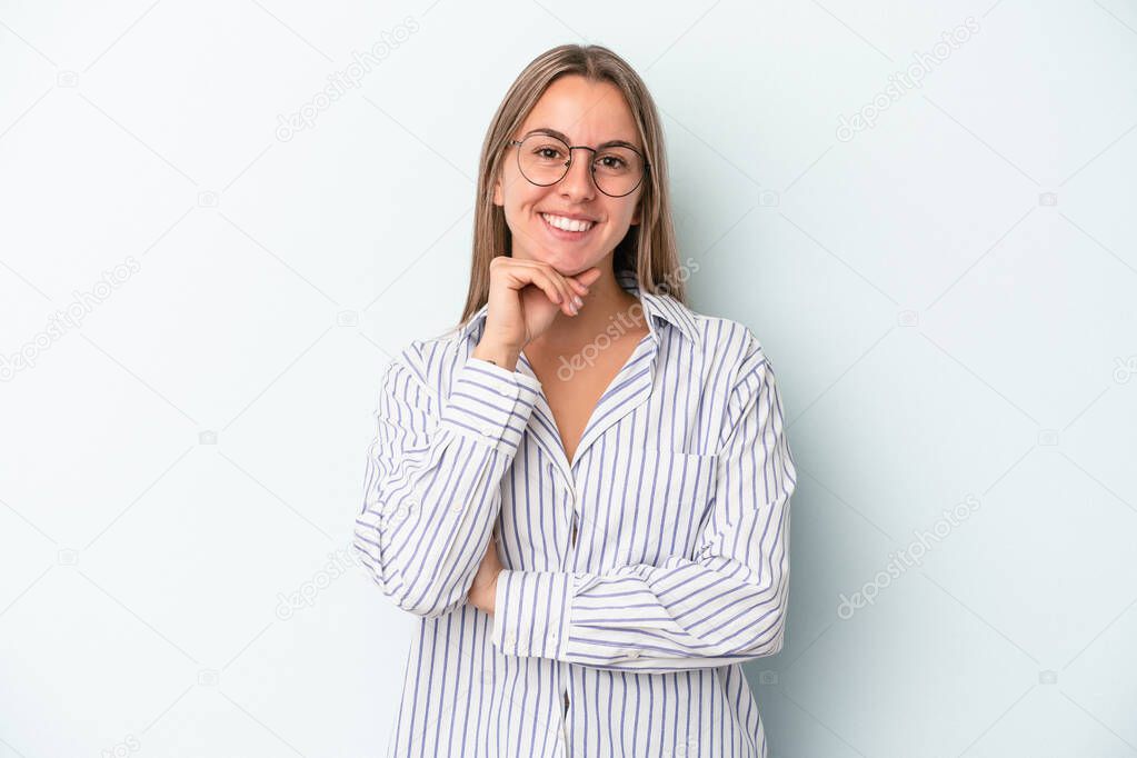 Young caucasian woman isolated on blue background smiling happy and confident, touching chin with hand.