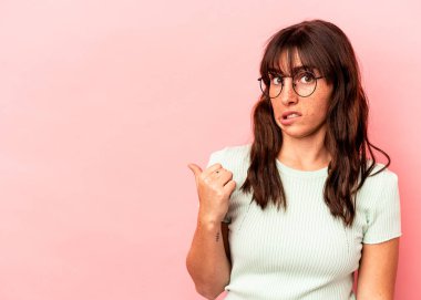 Pembe arka planda izole edilmiş genç Arjantinli kadın işaret parmağıyla fotokopi alanını işaret ederek şok oldu..