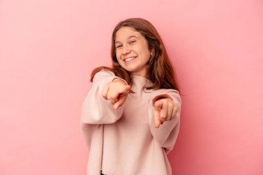 Pembe arka planda izole edilmiş küçük beyaz kız parmaklarıyla ön tarafı işaret ediyor..