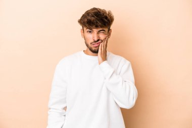 Young arab man isolated on beige background having a strong teeth pain, molar ache.