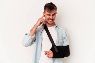 Kırık elli, beyaz arka planda izole edilmiş, elleri kulaklarında genç, beyaz bir adam..