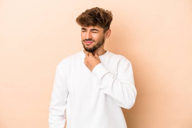 Young arab man isolated on beige background suffers pain in throat due a virus or infection.