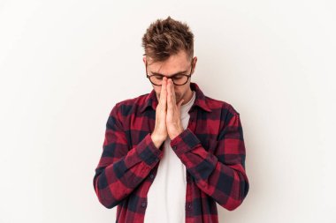 Beyaz arka planda izole edilmiş genç beyaz adam dua ediyor, bağlılık gösteriyor, dindar biri ilahi ilham arıyor..