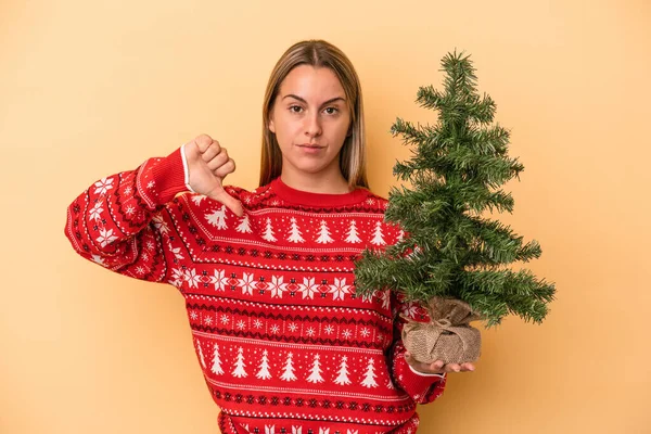 Mladá Běloška Držící Malý Vánoční Stromek Izolovaný Žlutém Pozadí Ukazující — Stock fotografie