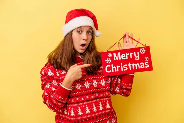 Malá Běloška Drží Veselý Vánoční Plakát Izolované Žlutém Pozadí Ukazuje — Stock fotografie