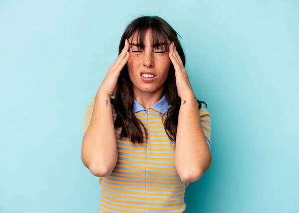 Young Argentinian woman isolated on blue background touching temples and having headache.