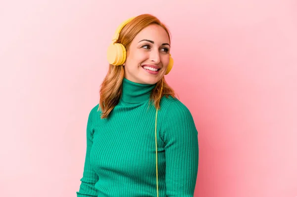 Young Caucasian Woman Listening Music Isolated Pink Background Looks Aside — Φωτογραφία Αρχείου