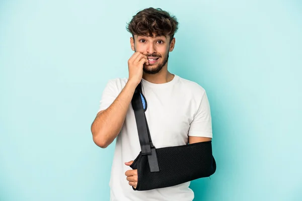 Young Arab Man Broken Hand Isolated Blue Background Biting Fingernails — 图库照片