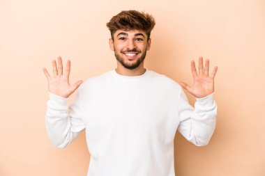 Young arab man isolated on beige background showing number ten with hands.