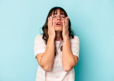 Arjantinli genç bir kadın mavi arka planda yalnız başına sızlanıyor ve ağlıyordu..