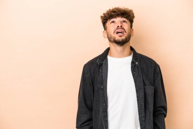 Young arab man isolated on beige background shouting very angry, rage concept, frustrated.