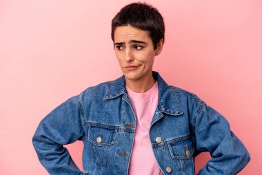 Kafkasyalı genç bir kadın mavi arka planda izole edilmiş, kafası karışmış, şüpheli ve kendinden emin değil..