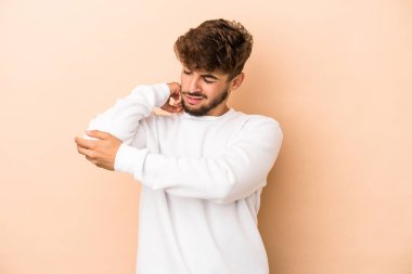 Young arab man isolated on beige background massaging elbow, suffering after a bad movement.