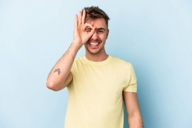 Kafkasyalı genç adam mavi arka planda izole edildi. Heyecanlı görünüyor..
