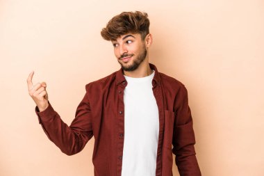 Genç Arap adam bej arka planda izole edilmiş seni işaret ediyor sanki davet ediliyormuş gibi..