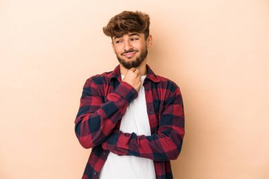 Young arab man isolated on beige background suffers pain in throat due a virus or infection.