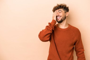 Young arab man isolated on beige background laughing happy, carefree, natural emotion.