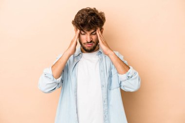 Young arab man isolated on beige background having a head ache, touching front of the face.