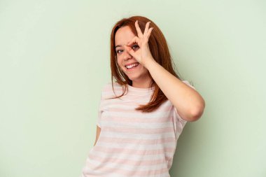 Genç beyaz kadın, yeşil arka planda izole edilmiş. Heyecanlı. Tamam, dikkatli ol..