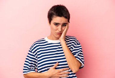 Mavi arka planda izole edilmiş genç beyaz kadın yanakları patlatıyor, yorgun bir ifadesi var. Yüz ifadesi kavramı.