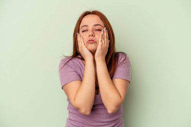 Genç beyaz kadın, yeşil arka planda izole edilmiş sızlanıyor ve ağlıyordu..