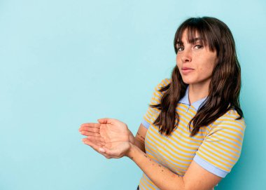 Arjantinli genç bir kadın mavi arka planda izole edilmiş. Elinde palmiye üzerinde bir kopya alanı var..