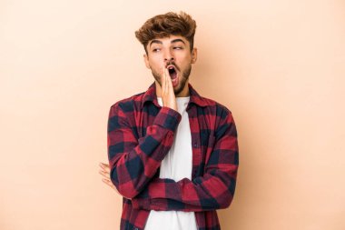 Young arab man isolated on beige background yawning showing a tired gesture covering mouth with hand.