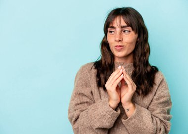 Genç Arjantinli kadın mavi arka planda izole edilmiş bir plan kuruyor, bir fikir kuruyor..