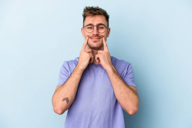 Kafkasyalı genç adam mavi arka planda izole edilmiş iki seçenek arasında şüphe duyuyor.