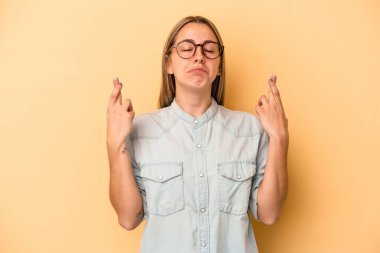 Sarı arka planda izole edilmiş beyaz bir kadın şans dilemek için şans diliyor.