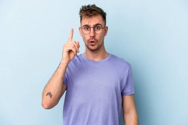 Kafkasyalı genç bir adam mavi arka planda izole edilmiş. Bir fikri, ilham verici bir fikri var..