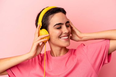 Pembe arka planda izole edilmiş müzik dinleyen beyaz bir kadın.