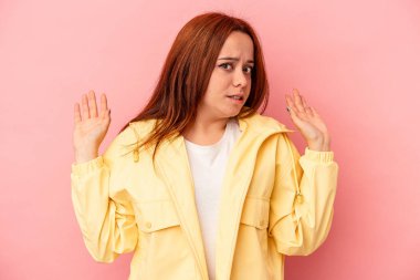 Pembe arka planda izole edilmiş genç beyaz kadın yakın bir tehlike nedeniyle şoka uğruyor.