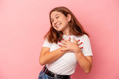 Pembe arka planda izole edilmiş küçük beyaz kız, dostane bir ifadeye sahip, avuçlarını göğsüne bastırıyor. Aşk konsepti.