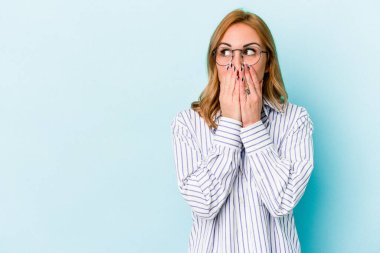 Kafkasyalı genç bir kadın mavi arka planda izole edilmiş düşünceli bir şekilde ağzıyla ağzını kapatan bir fotokopi odasına bakıyor..