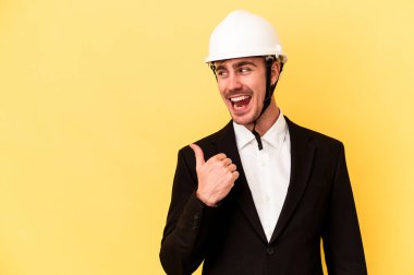 Genç mimar beyaz adam sarı arka plan noktalarında izole edilmiş başparmak uzakta, gülüyor ve kaygısız.