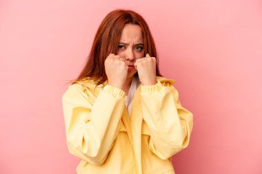 Pembe arka planda izole edilmiş genç beyaz kadın bir tartışma yüzünden yumruk, öfke, kavga ve boks atıyor..