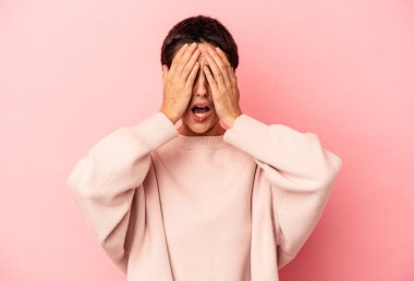 Mavi arka planda izole edilmiş genç beyaz kadın yüzünün yarısını palmiyeyle kaplarken eğleniyor..