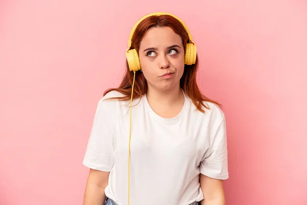 Jonge Blanke Vrouw Luisteren Naar Muziek Geïsoleerd Roze Achtergrond Verward — Stockfoto