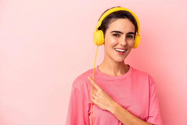 Young Caucasian Woman Listening Music Isolated Pink Background Smiling Pointing — Φωτογραφία Αρχείου