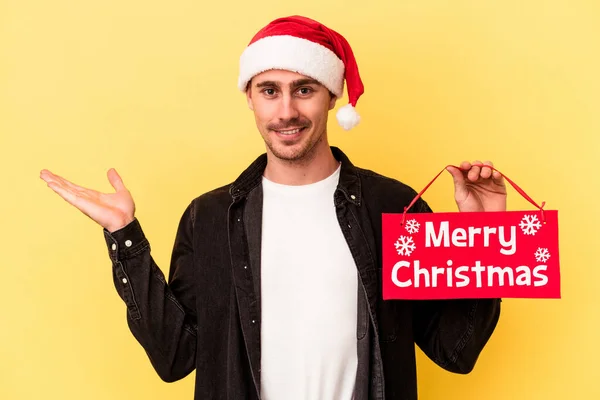 Mladý Běloch Drží Veselé Vánoční Plakát Izolované Žlutém Pozadí Zobrazující — Stock fotografie