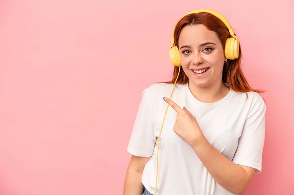Joven Mujer Caucásica Escuchando Música Aislada Sobre Fondo Rosa Sonriendo —  Fotos de Stock