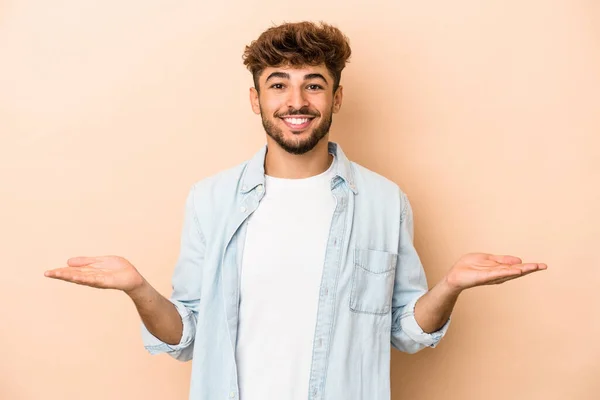 Young Arab Man Isolated Beige Background Makes Scale Arms Feels — Stock fotografie