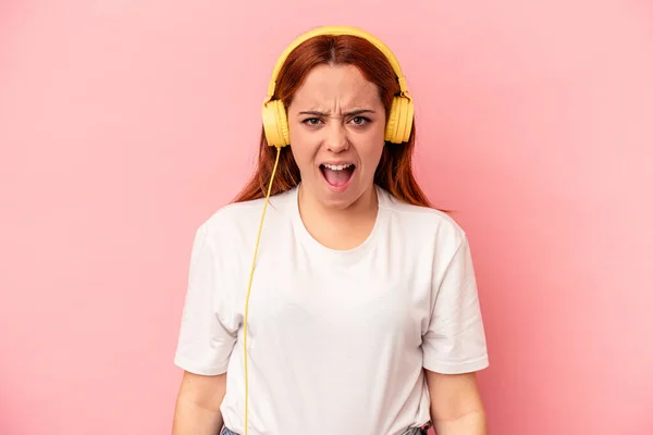 Young Caucasian Woman Listening Music Isolated Pink Background Screaming Very — Φωτογραφία Αρχείου
