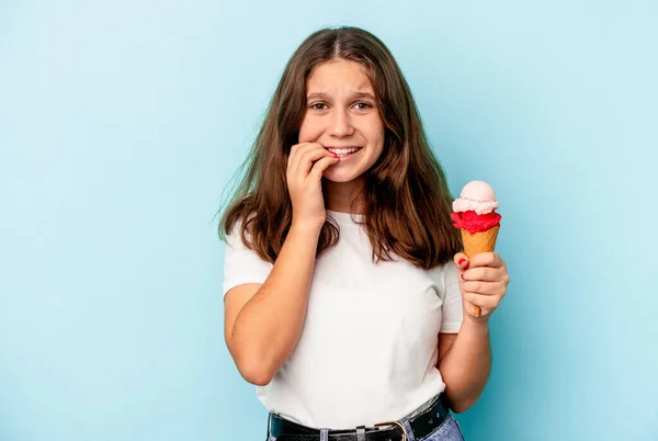 小女孩吃着用蓝色背景隔离的冰淇淋 咬着指甲 很紧张 很焦虑 — 图库照片