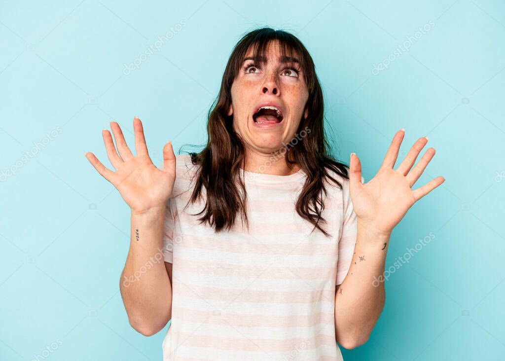 Young Argentinian woman isolated on blue background screaming to the sky, looking up, frustrated.