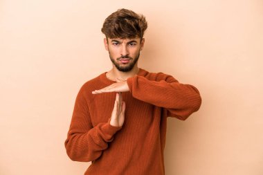 Young arab man isolated on beige background showing a timeout gesture.