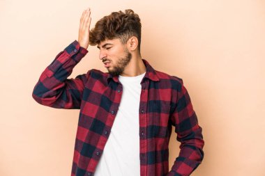 Young arab man isolated on beige background forgetting something, slapping forehead with palm and closing eyes.
