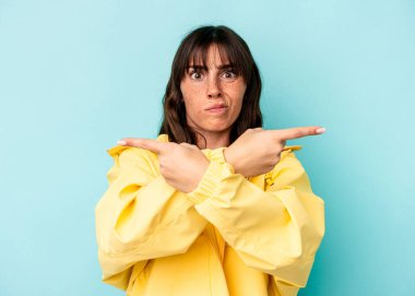 Arjantinli genç bir kadın mavi arka planda iki seçenek arasında seçim yapmaya çalışıyor..