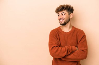Young arab man isolated on beige background smiling confident with crossed arms.